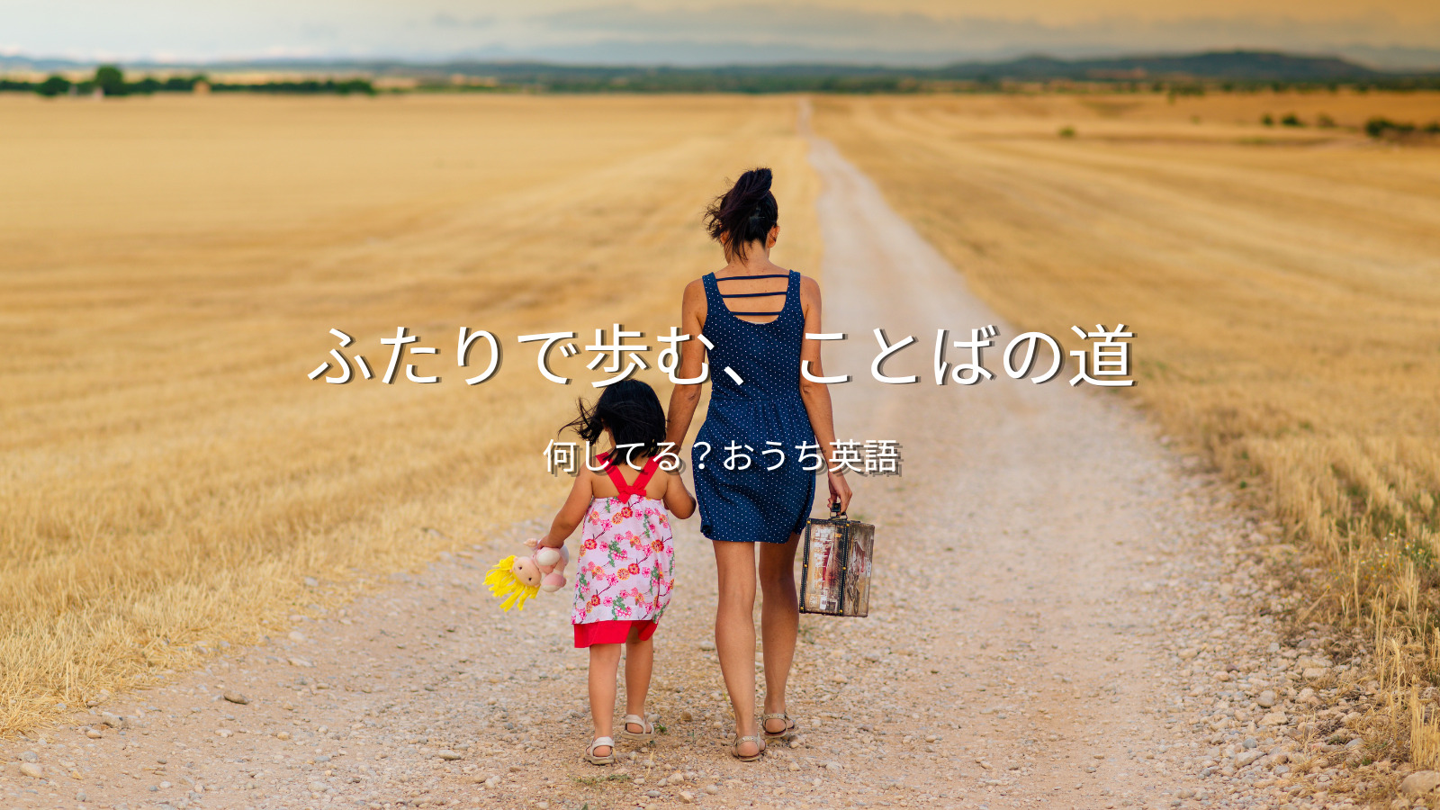小麦畑を歩く親子の後ろ姿と「ふたりで歩む、ことばの道」のキャッチコピー｜おうち英語